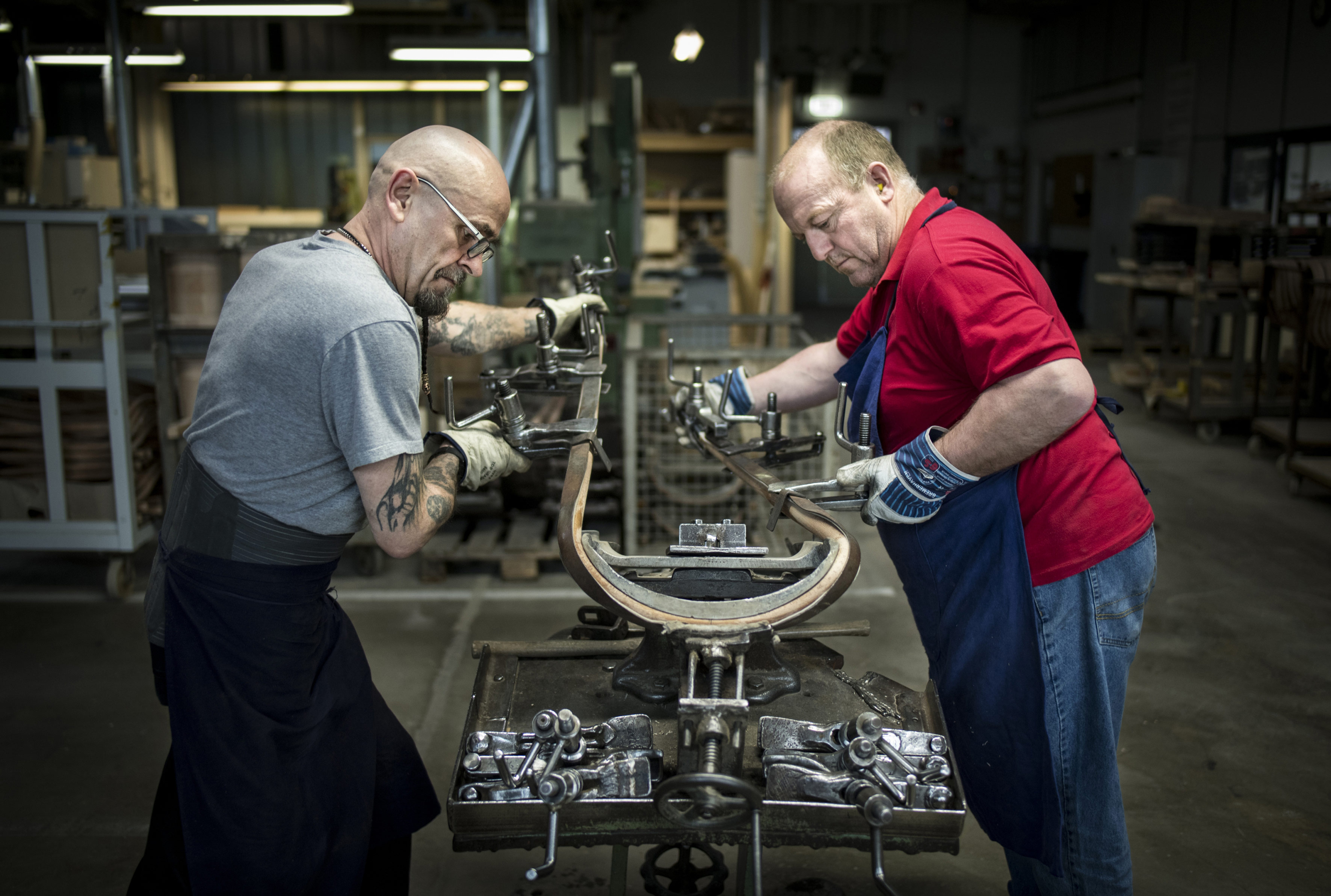 Zwei Mitarbeiter von Thonet biegen Holz für einen Bugholzmöbelstuhl