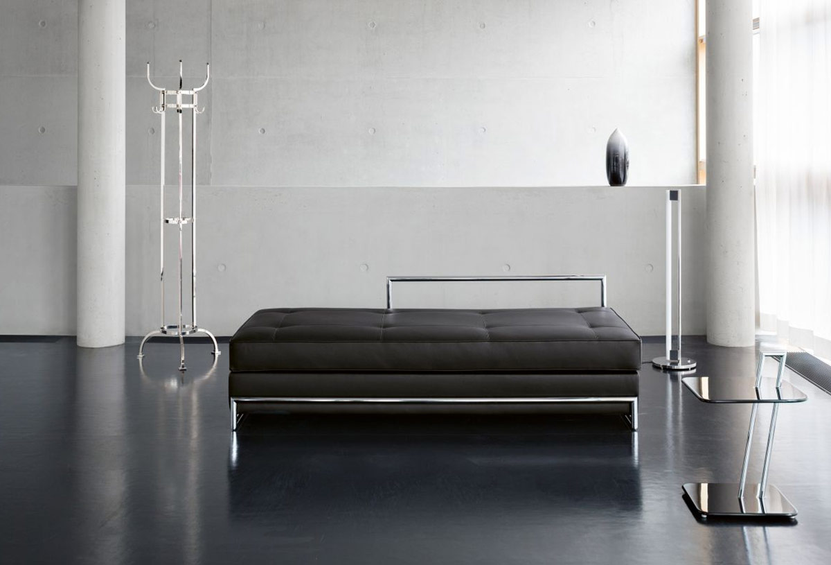 Die Classicon Möbel Garderobe Nymphenburg, Day Bed, Tube Light und Occasional Table vor einer Betonwand auf schwarzem Boden